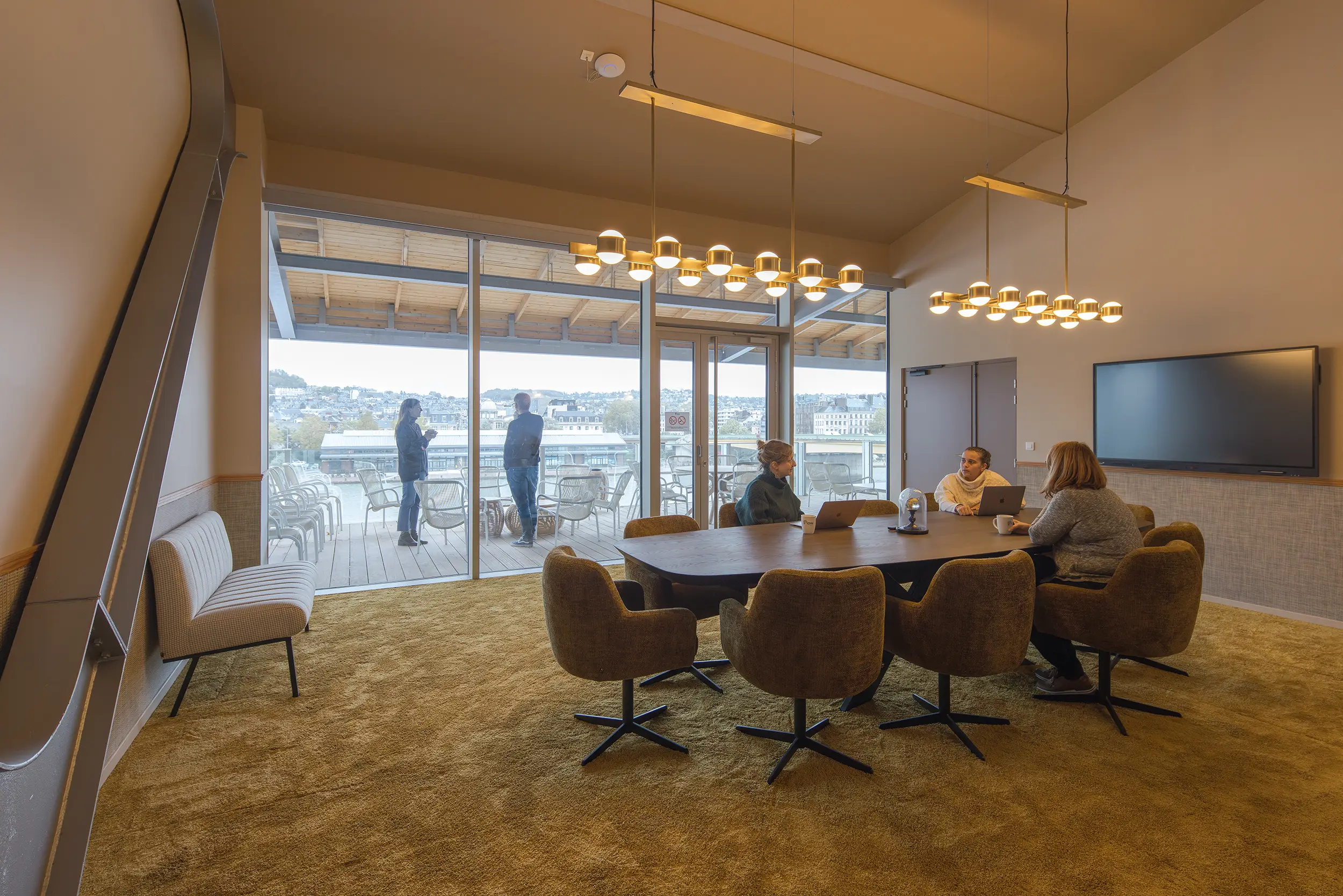 Professionnels travaillant dans une salle de réunion de Now Coworking Rouen avec vue sur la terrasse, un espace pour vos séminaires et événements d’entreprise avec le Groupe Silam.